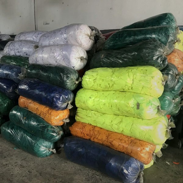 Galpão da Workday Resíduos: pilhas de resíduos têxteis separados por cor, prontos para reciclagem.
